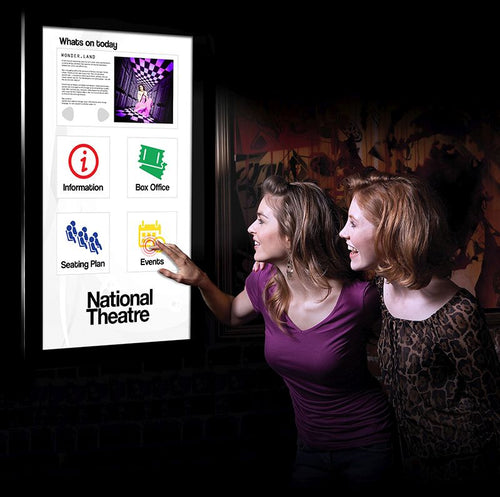 Two ladies finding out about the National Theatre events on one of our touch screens